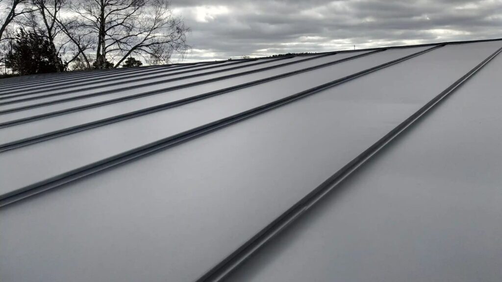 Close-up of a gray standing-seam metal roof under an overcast sky