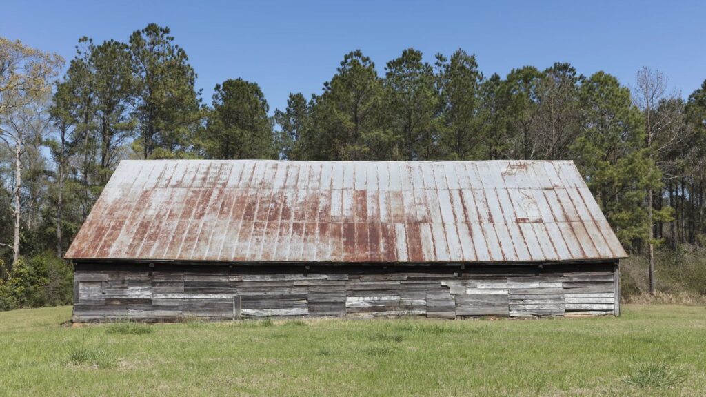 Old wood barn with a rusted metal roof in a field