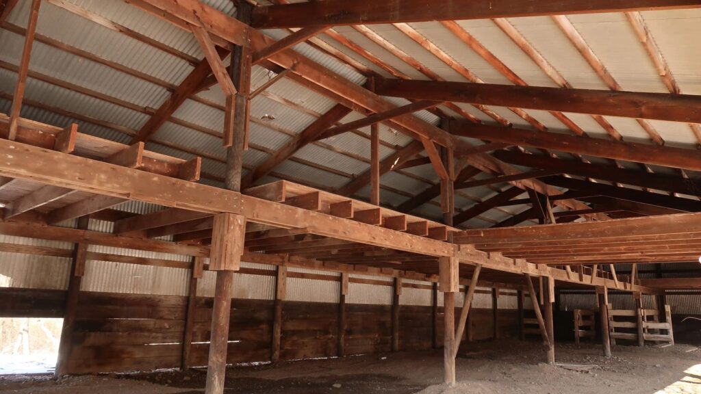 Interior of a wood pole barn with timber posts, beams, and a metal roof