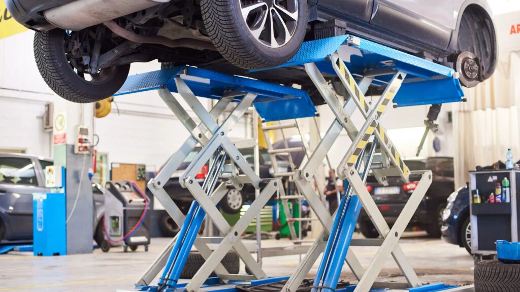 Car raised on a vehicle lift inside an auto repair shop