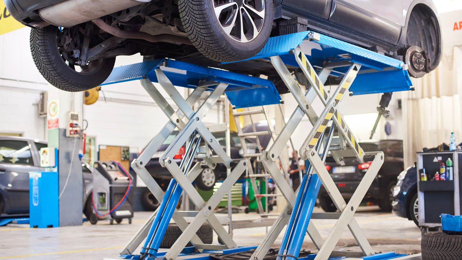 Car raised on a vehicle lift inside an auto repair shop